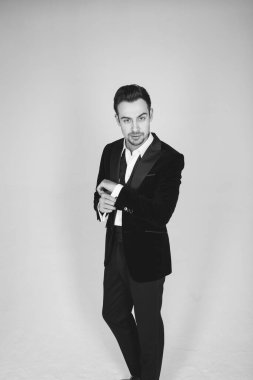 Smokinli genç beyaz bir adamın stüdyo portresi, kameraya bakıyor, düz stüdyo arka planında duruyor.