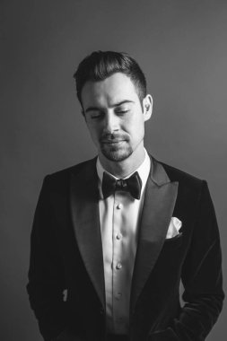 Smokinli beyaz bir adamın stüdyo portresi, ne yazık ki, düz stüdyo arka planına bakıyor.