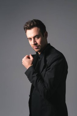 Siyah ceketli beyaz bir adamın stüdyo portresi. Kameraya bakıyor. Stüdyonun arka planında duruyor.