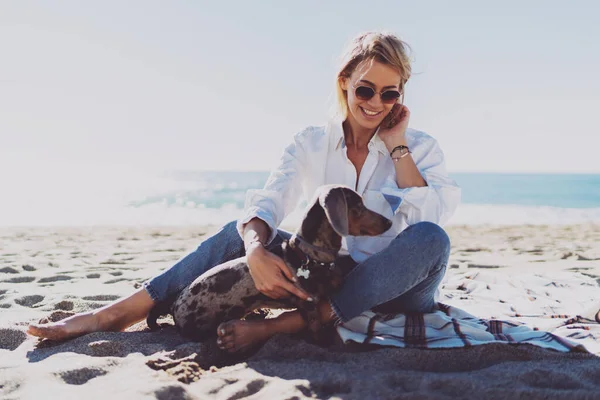 Модель Выглядит Блондинкой Улыбающейся Глядя Свою Милую Собаку Отдыхающую Пляже — стоковое фото