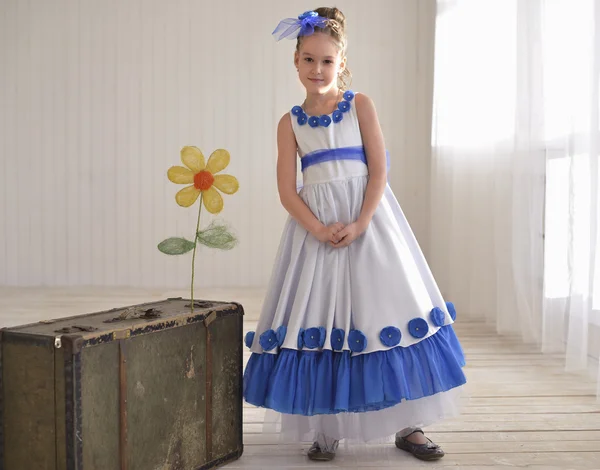 Kleines Mädchen sitzt neben alter Tasche mit Blume — Stockfoto