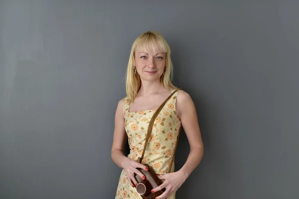 Hermosa mujer sosteniendo la cámara vieja, de pie sobre fondo gris — Foto de Stock