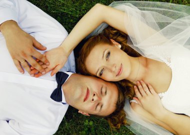 çim üzerinde yalan ve el ele tutuşarak yeni evli bir çift portre portre