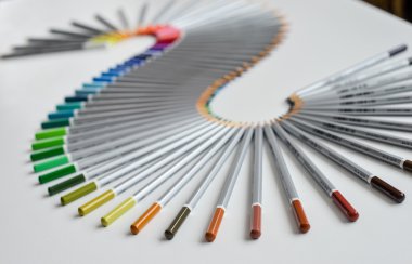 Beyaz arka plan üzerinde izole bir dalga düzenlenen renkli kalemler