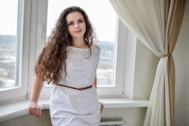 Genç ve güzel esmer kadın pencerenin poz