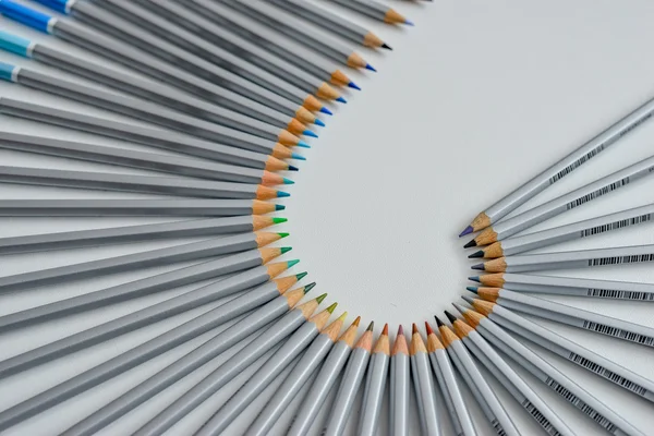 Lápis coloridos dispostos em uma onda isolada sobre fundo branco — Fotografia de Stock