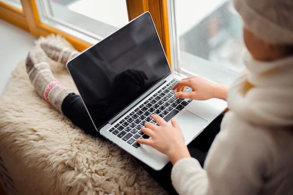 Cute girl with long hair sitting alone near window  with laptop — Stock Photo, Image