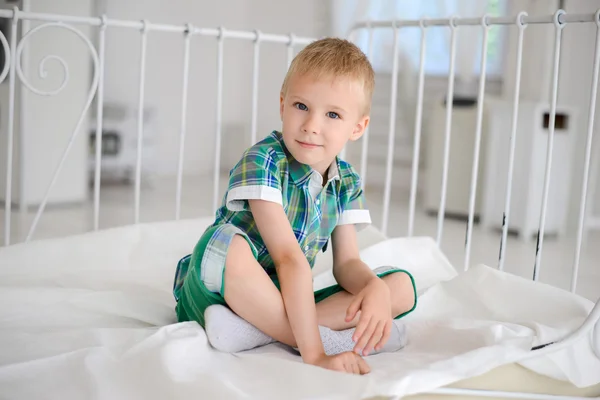 Niño sentado en la cama grande —  Fotos de Stock