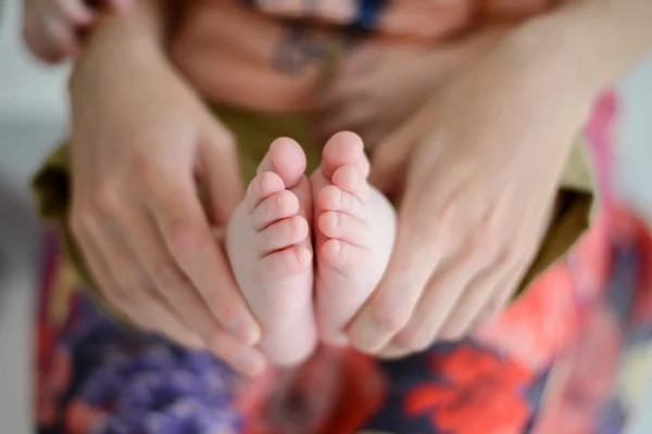 Mother holds the feet of the newborn child — Stock Photo, Image
