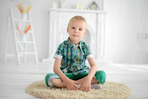 Pequeño niño pensativo sentado en el suelo en casa —  Fotos de Stock
