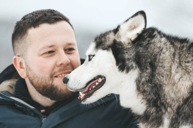 Kış ormanlarında ve parkta Sibirya Husky 'siyle oynayan adamlar.