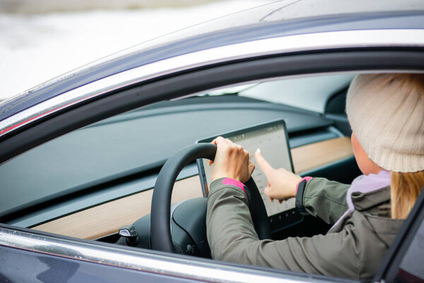 Мясник. БЕЛАРУС - ЯНВАРЬ 2021: Красивая женщина смотрит на ноутбук электромобиля.