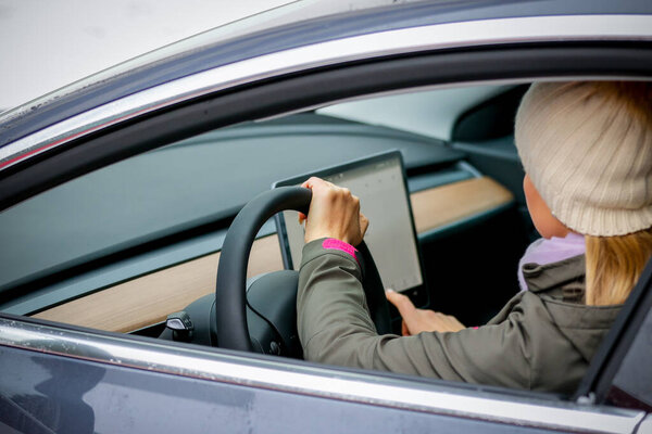 Мясник. БЕЛАРУС - ЯНВАРЬ 2021: Красивая женщина смотрит на ноутбук электромобиля.