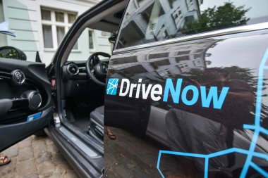 ALMANY - AĞUSTOS 2015: DriveNow adlı bir şirketten kiralama için bir Minicooper 'ın üzerindeki şirket tabelasına yakın çekim. Araba kiralama bir mobil uygulama aracılığıyla gerçekleştirilir.