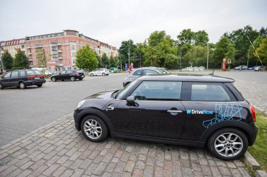 ALMANY - 2015 AĞUSTOS: Şehirde bir otoparkta araba paylaşımı. Minicooper 'daki şirket tabelasına yakın çekim. Araba kiralama bir mobil uygulama aracılığıyla gerçekleştirilir.