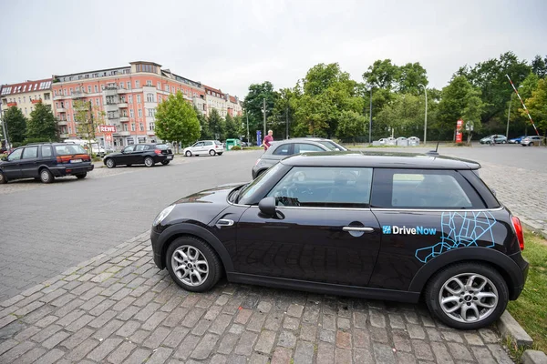 GERMANY - AUGUST 2015: Car sharing car in a parking lot in the city. Close-up of a company sign on Minicooper for rent from DriveNow. Car rental takes place through a mobile application. — Stock Photo, Image