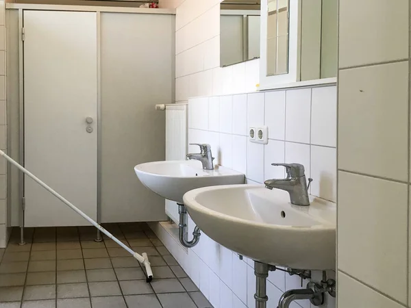 GERMANY - MAY 2016: Interior of an old bathroom. White washbasins, doors. — Stockfoto