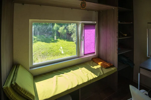 MINSK. BELARUS - maj 2016: Wnętrze pokoju z sofą przy oknie, jasnozielona sofa przy oknie z widokiem na zieloną trawę. — Zdjęcie stockowe