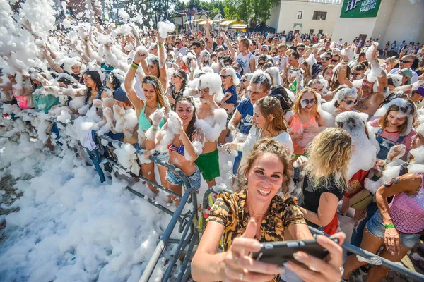 MINSK. BELARO - Giugno 2016: Ritratti di persone felici in schiuma a una festa. schiuma partito divertente, la gente allegramente alza le mani, prendere bolle di sapone, festival di intrattenimento estivo in acqua — Foto Stock