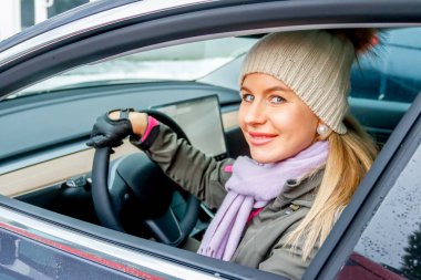Vizon. BELARUS - 20 Ocak 2021: Güzel bir kadın elektrikli bir arabanın camından dışarı bakar.