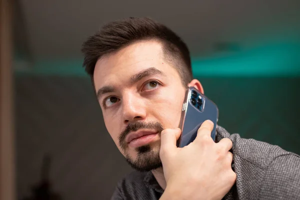 El hombre trabaja desde casa, hablando en un dispositivo móvil. La comunicación con el cliente lo es todo. — Foto de Stock