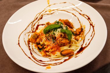 Midyeli makarna, beyaz tabakta soslu servis..