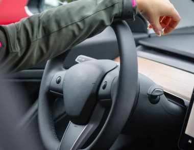 Elektrikli bir arabanın direksiyonunda bir kadın eli. Elektrikli araba gösterge paneli.