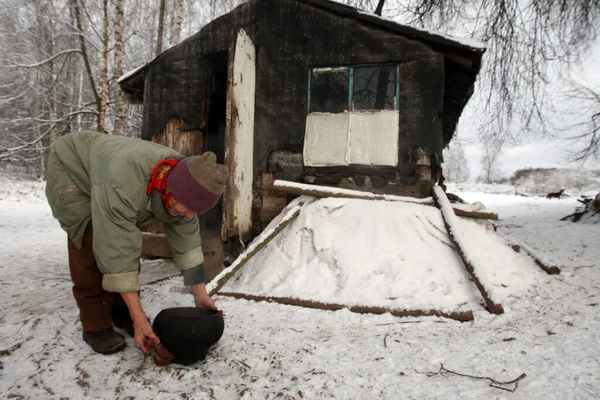 Bielorrússia. Village Small Volneyki - 28,11,2010: Inverno na aldeia. Mulher caminha com baldes contra o pano de fundo da luz solar. — Fotografia de Stock