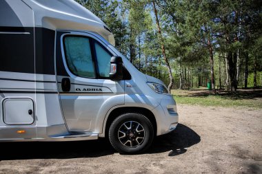 Belarus - 11.05.2021 - Gölün arka planında bir kampçı. Göl kenarındaki mobil ev..