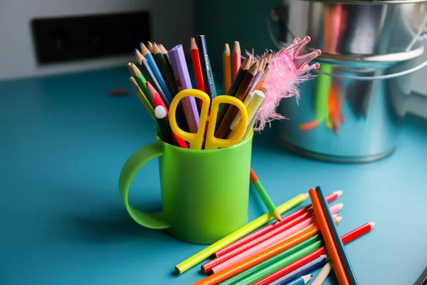 Lápis coloridos em um círculo verde em uma mesa azul. Muitos lápis de cor diferentes. Papelaria. — Fotografia de Stock