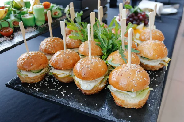 Set de varias hamburguesas para catering. Hamburguesas en un plato negro en la mesa buffet. —  Fotos de Stock