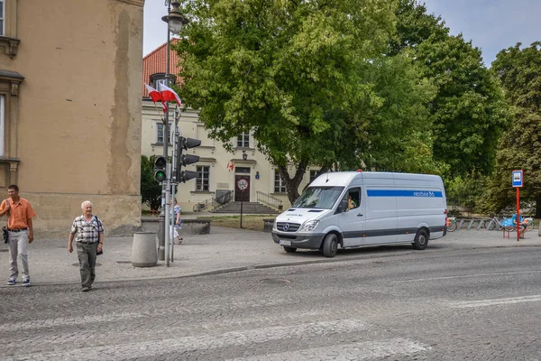 WARSAW. POLONIA - Agosto de 2015: Coche de policía en el centro de Varsovia en el casco antiguo. Un coche de policía blanco con un logotipo azul se encuentra entre una parada de transporte público con un cruce peatonal. — Foto de Stock