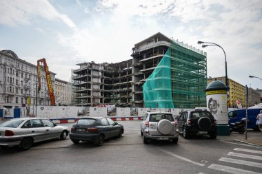 Dikkatli ol. POLAND - 2015 AĞUSTOS: Şehirde yeni bir bina inşaatı. Arabalar yol boyunca park halinde. İnşaat makineleri.