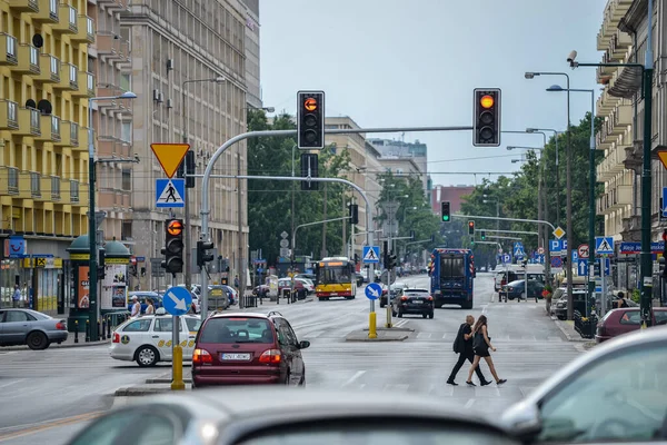 WARSAW. POLONIA - AGOSTO 2015: La carretera en la ciudad, el tráfico de la ciudad, los semáforos, el semáforo amarillo está encendido, la gente está cruzando la carretera. — Foto de Stock