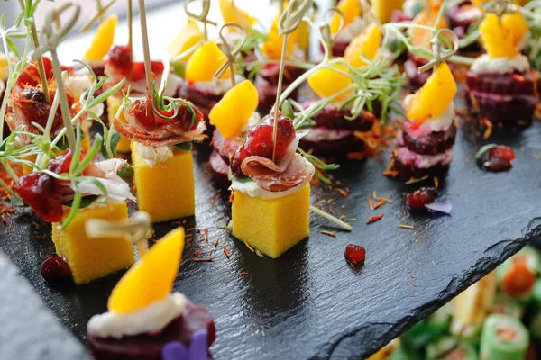 A set of mango, bacon and greens appetizers on a buffet table — Stock Photo, Image