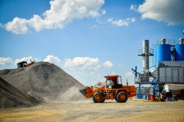 Makineler asfalt üretimi için malzeme yükleme ve boşaltma üzerinde çalışırlar. Asfalt bitkisi.