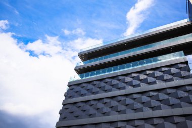 Mavi gökyüzü ve bulutların arka planına karşı orijinal cepheli yeni bina.