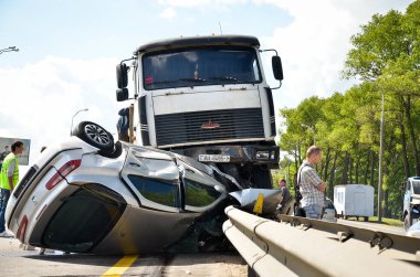 Bypass yolunda araba kazası. Adam, MAZ ile çarpıştıktan sonra Renault Tuareg arabasının yanında oturuyor.. 