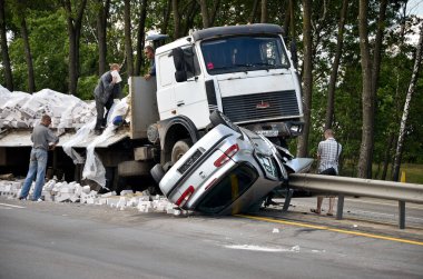 Bypass yolunda araba kazası. Adam, MAZ ile çarpıştıktan sonra Renault Tuareg arabasının yanında oturuyor.. 