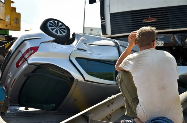 在与MAZ相撞后，一个人坐在一辆撞毁的雷诺 · 图阿雷格汽车旁边。绕行公路上的车祸. — 图库照片