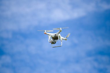 White drone in the blue sky with clouds.