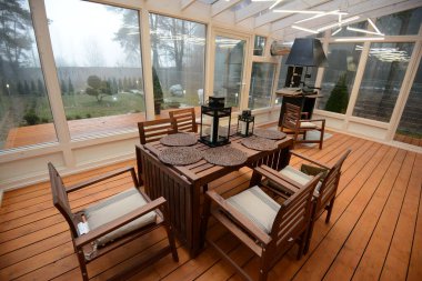 Ahşap masa ve koltuklar iç kısımda. Evde eko stili var. Evde doğal malzemeler var..