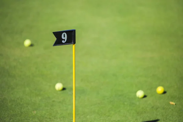 Bandiera in una buca da golf su uno sfondo di erba verde e palline da golf. Golf, buca da golf. — Foto Stock