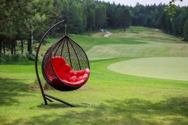 Golf sahasında kırmızı ekoseli asılı sandalye.