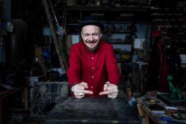 Man in a hat shows a fuck, a man in a red shirt in a workshop expresses emotions
