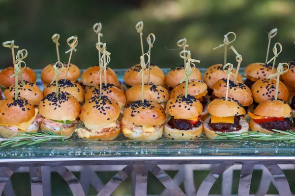 Mini hamburgery z czarnymi nasionami sezamu przy stole bufetowym — Zdjęcie stockowe