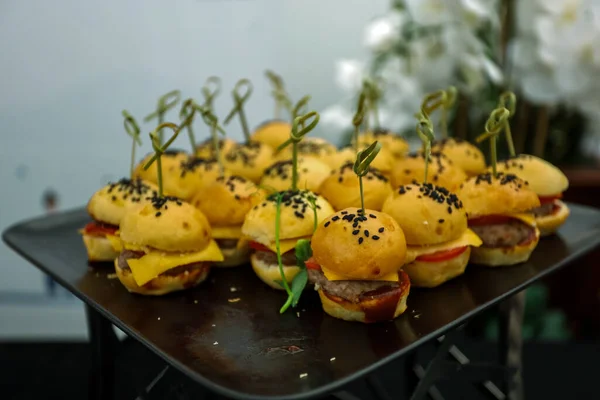 Mini hamburguesas con semillas de sésamo negro. Catering, comida en mesa buffet en plato blanco en la calle —  Fotos de Stock
