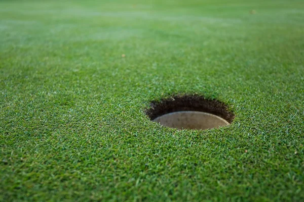 Buraco de bola em um campo de golfe verde — Fotografia de Stock