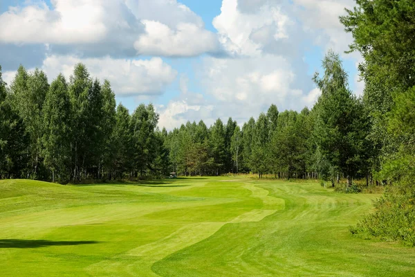 Lapangan golf, lansekap, rumput hijau di latar belakang hutan dan langit cerah dengan awan Stok Gambar Bebas Royalti