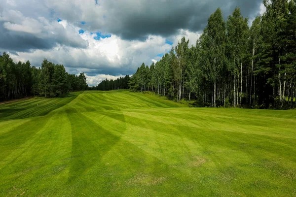 Campo de golfe, paisagem, grama verde no fundo de uma floresta e um céu brilhante com nuvens — Fotografia de Stock
